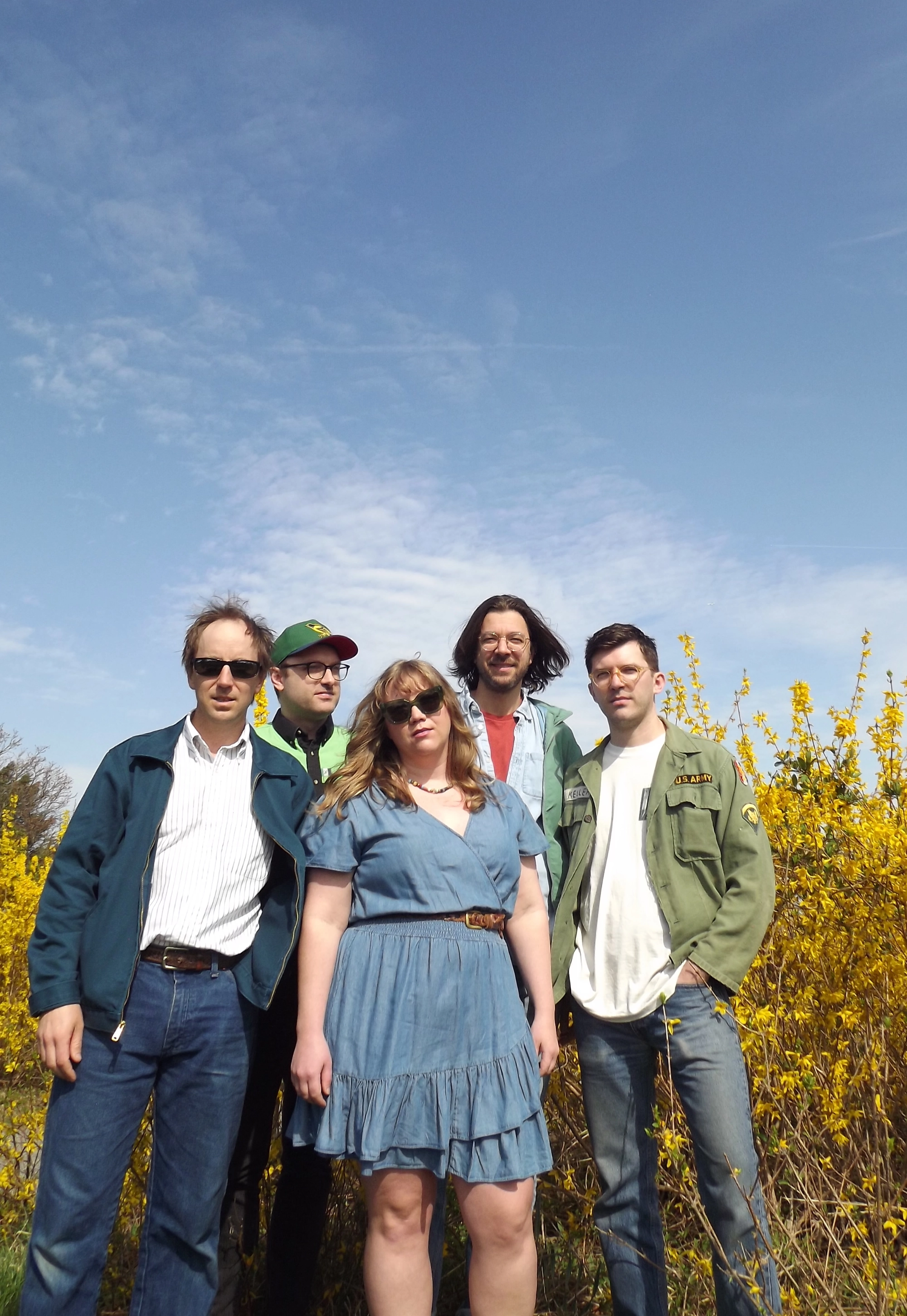 Matt, Greg, Sophie, Matt and Nick of Worn Through standing in front of beautiful yellow forsythias with a huge blue sky in the background.