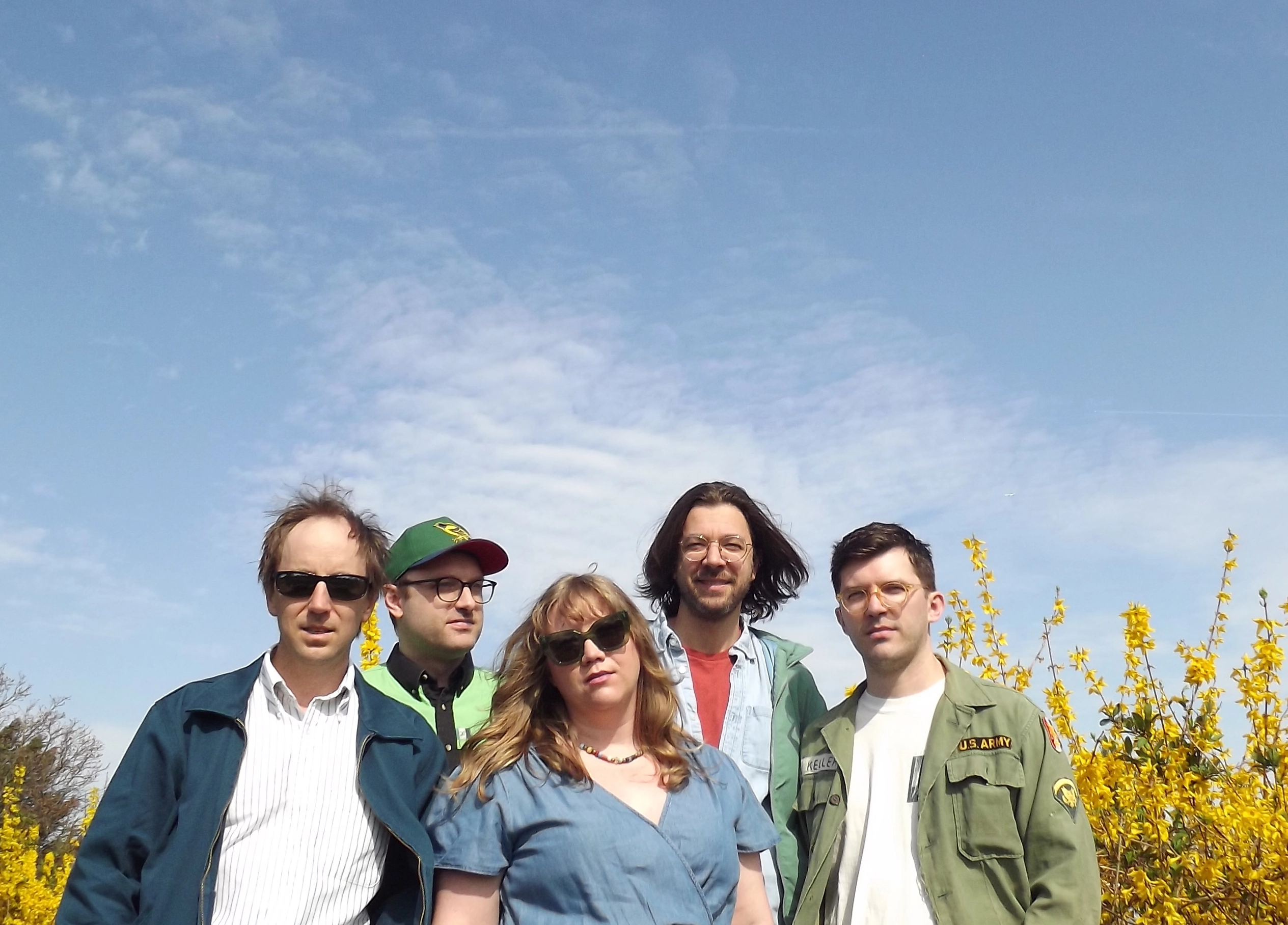 Matt, Greg, Sophie, Matt and Nick of Worn Through standing in front of beautiful yellow forsythias with a huge blue sky in the background.